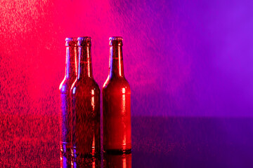 Image of three brown beer bottles with crown caps, with copy space on red and purple background - obrazy, fototapety, plakaty