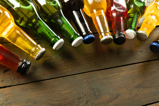 Image of various coloured glass beer bottles with crown caps, with copy space lying on wood