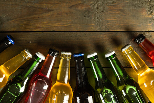 Image of various coloured glass beer bottles with crown caps lying on wood, with copy space