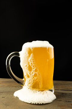 Naklejka Image of glass tankard full of foamy beer on wooden table, with copy space