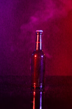Image of brown glass lager beer bottle with crown cap, with copy space on smokey background