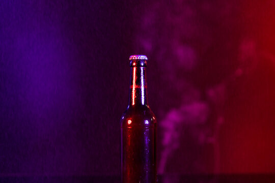 Image of brown glass lager beer bottle with crown cap, with copy space on smokey background