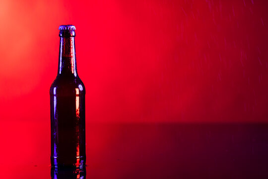 Image of brown glass lager beer bottle with crown cap, with copy space on red background