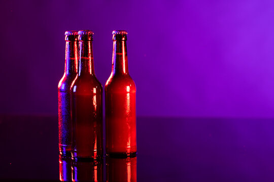 Image of three brown beer bottles with crown caps, with copy space on purple background