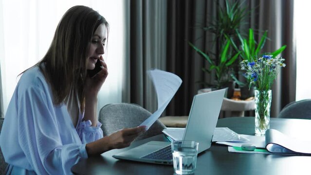Young lady holding documents, talking on phone and explaining, shouting. Nervious boss is angry, finding a mistake in documents. Cooperate with colleagues