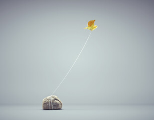 Bird tied to a rock flying away. Confidence and mindset concept. - obrazy, fototapety, plakaty