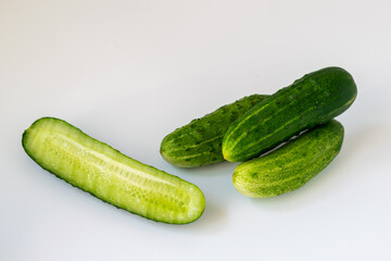Fresh whole and half sectioned cucumbers on white natural background, diet and detox, product