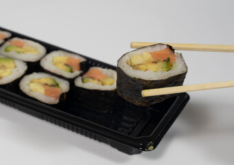 chopsticks grabing a piece of sushi from a sushi set