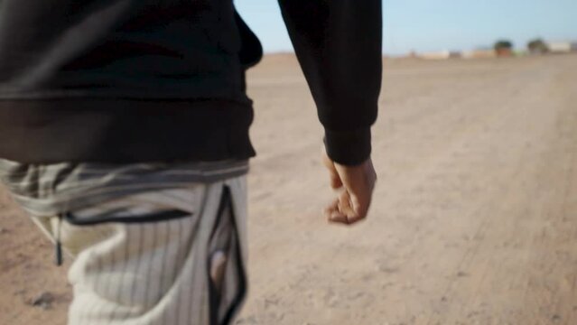 Closeup shot of a male with striped pants walking on a sandy desert