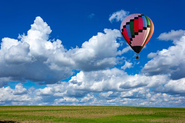 Colorful hot air balloons over green rice field.