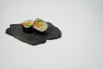 two pieces of sushi in a blackboard plate with white background