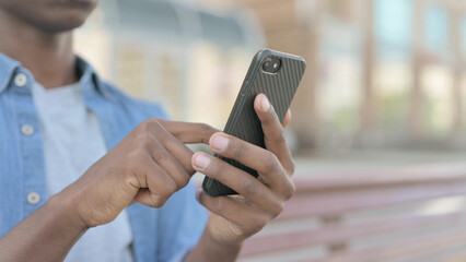 Close Up of Young African Man Using Smartphone while Sitting Outdoor on Bench