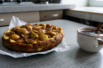 Cottage cheese casserole pie with raisins and caramelized pears on top with the cup of black coffee with cinnamon.