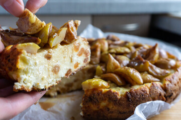 Cottage cheese casserole pie with raisins and caramelized pears on top. Woman putting pear on top.