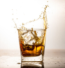 Portrait of whiskey splash glass with ice isolated on white background studio.