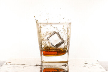 Portrait of whiskey splash glass with ice isolated on white background studio.