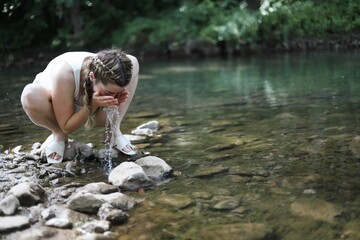Closeup of a girl washing her face in a river