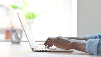 Side View of Young African Man Typing on Laptop Keyboard