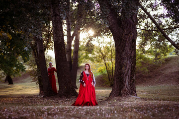 Naklejka premium Living history: a 15th-century woman dressed as a wealthy lady in a Venice dress and her maid in the woods