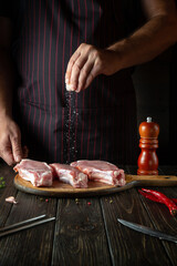 The chef sprinkles raw ribs with salt. The concept of cooking delicious food for the hotel or restaurant
