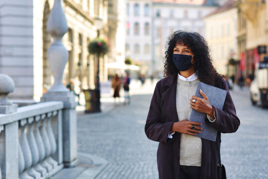 businesswoman outdoors with face mask holding folder documents