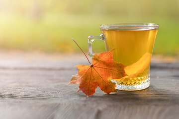 Autumn still life with a teacup with a slice of lemon on wooden boards and a blurred background in...