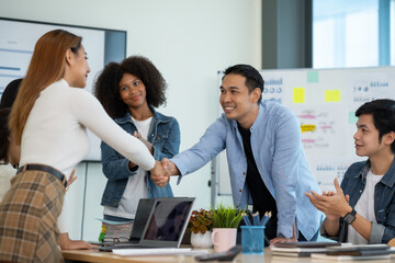 Happy young Asian businessman shaking hand congratulating success of the other business executives shake hand to congratulate on the future business cooperation agreement.