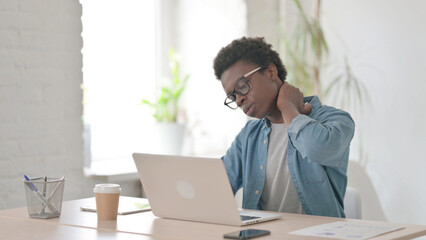 Young African Man having Neck Pain while using Laptop in Office