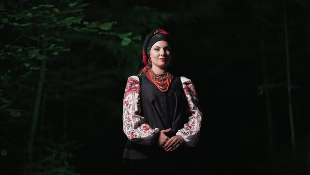 Beautiful woman in traditional ukrainian handkerchief, necklace and costume on night forest background. Lady in national dress - vyshyvanka, ancient coral beads. Concept of ethnic style, traditions