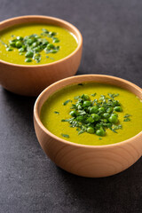 Green pea soup in a bowl on black background