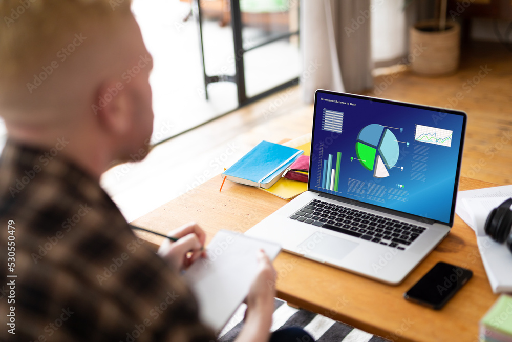 Poster albino african american man using laptop and making notes with charts and data on screen