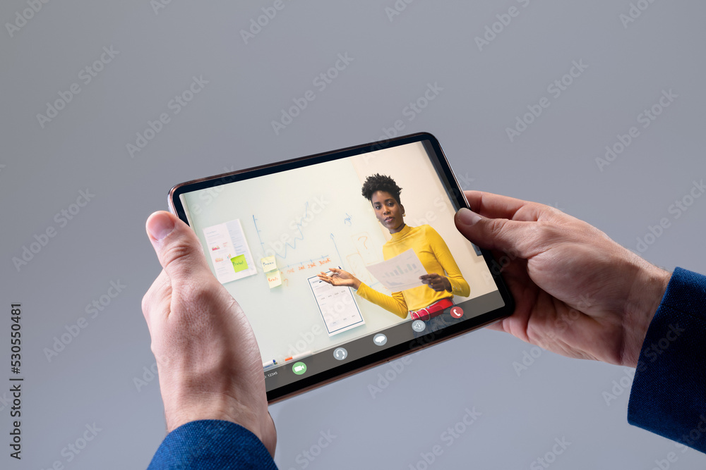 Poster Hands of caucasian businessman making video call on tablet with diverse female colleague on screen