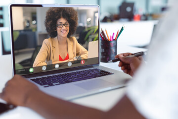 Midsection of african american businesswoman making laptop video call with biracial female colleague - Powered by Adobe