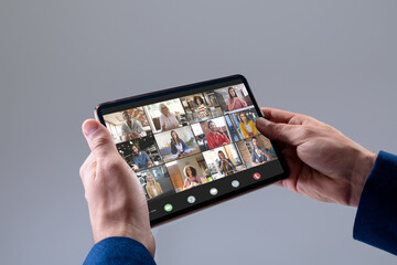 Hands of caucasian businessman making video call on tablet with diverse colleagues on screen