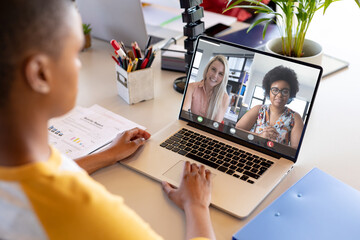 African american woman at desk making laptop video call with two diverse female colleagues on screen