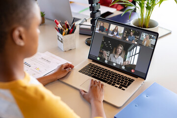 African american businesswoman at desk making laptop video call with diverse colleagues on screen