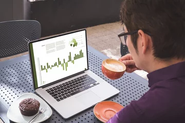 Keuken foto achterwand Aziatische plekken Aziatische zakenman aan tafel in café met laptop met grafieken en gegevens op het scherm