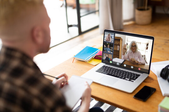 Albino african american man making laptop video call with diverse colleagues on screen