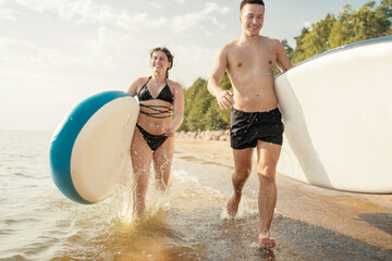 People man and woman running riding water sport sup board.