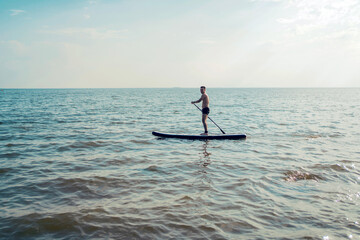 A man on a weekend vacation riding a sup board on the sea.