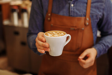 ready coffee in the hands of a barista in a coffee shop
