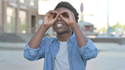Outdoor Young African Man Searching with Handmade Binocular