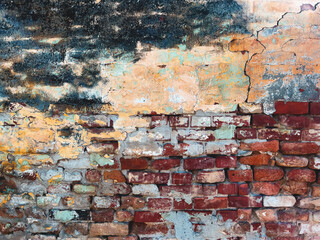 Very old brick wall with cracks and damaged stucco surface, worn layers of paint peeling off. Grunge texture and background.