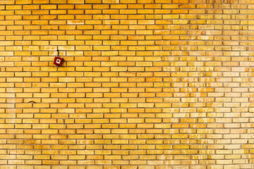 Yellow brick wall with fire alarm button
