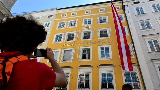 Salzburg, Austria, August 2022. A cute boy is photographing mozart's house with his cellphone as a souvenir of the holiday.