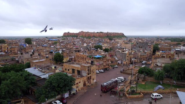 Aerial drone view of Jaisalmer city and fort while many pigeons are flying around