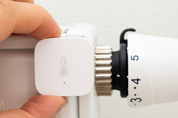 Heat sensor on the battery for temperature control and man hand installing it. The increasing price of gas and heating concept