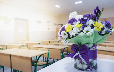 A bouquet of autumn flowers lies on a table in the classroom. Greeting card with the beginning of the school year at school. High quality photo