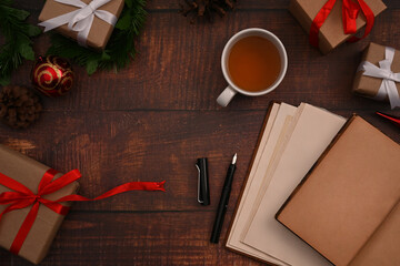 Cup of herbal tea, notebook, Christmas gift box and fir tree branch on wooden background