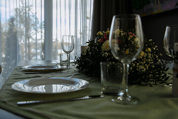 in a bright room, with daylight, a festive table is decorated, with plates and glasses